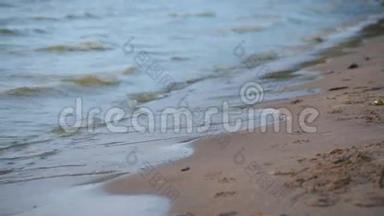 靠近海浪，柔和的海浪在日落时的沙滩上冲着阳光反射
